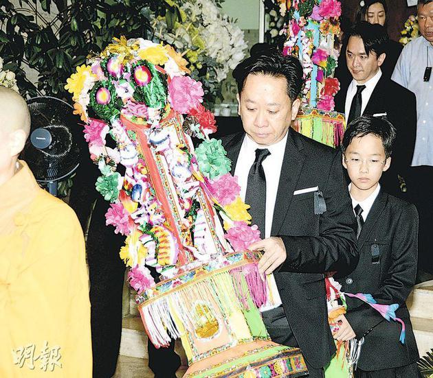 哭得鼻子通红的邓兆荣与儿子随僧侣从灵堂出来。