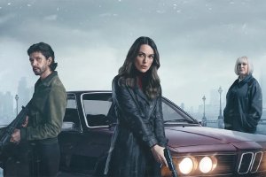 車のそばに立つ男女と、奥に立つ人物を描いた『ブラック・ダヴ』の場面写真。