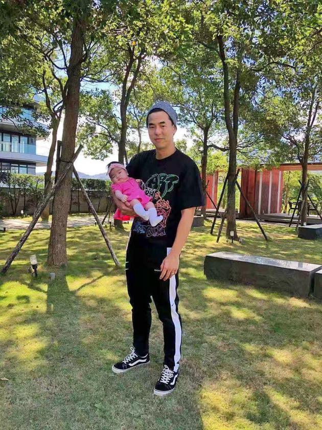  Ke Youlun holds his daughter with one hand 