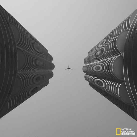 　　2013/10 | 美国芝加哥市马里纳城（Marina City）　　常见的Marina City的照片多为侧视视角，像两个巨大的玉米立在楼群中。这张照片我选择了仰视的角度，增加了空间的纵深感，而且利用了对称构图让在建筑间隙碰巧飞过的飞机成为视觉中心。　　iPhone 5 | Filterstorm，VSCO Cam