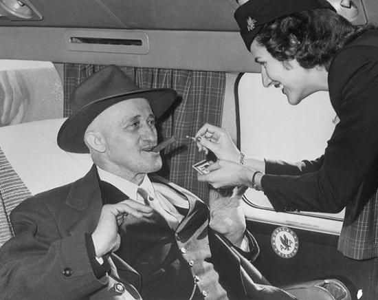 1949年11月10日，东圣路易斯航空公司空姐Jane Driscoll为68岁的Carl Graulein点雪茄。