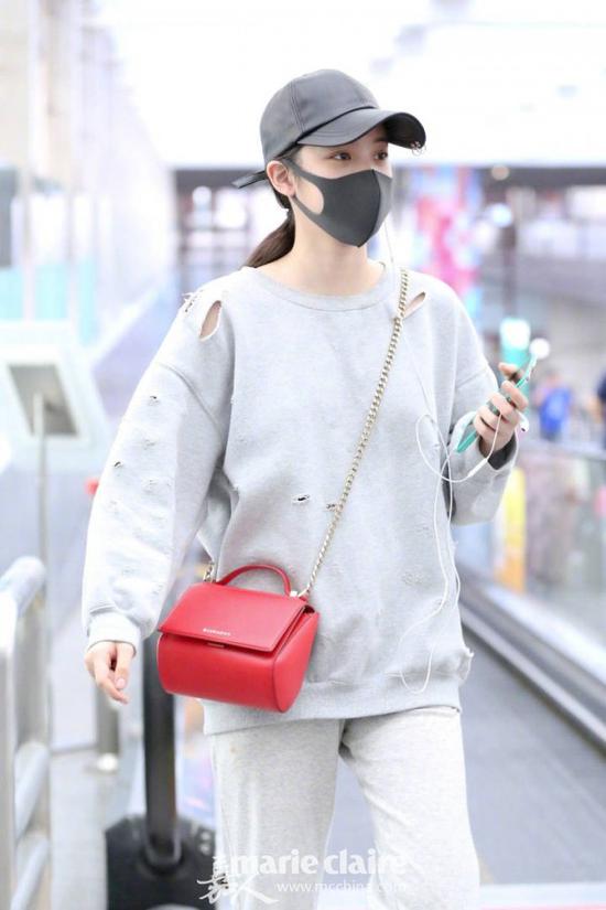 街拍中，欧阳娜娜戴黑色棒球帽，身穿灰色长袖破洞卫衣，下穿灰色运动裤，斜跨Givenchy红色潘多拉手袋。