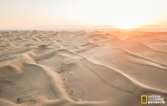 初升太阳的光芒照在层次分明的腾格里沙漠上。