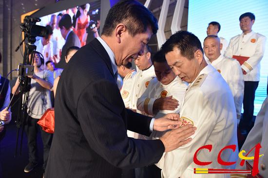 在授勋仪式上，中国烹饪协会会长姜俊贤为注册中国烹饪大师贴袖标