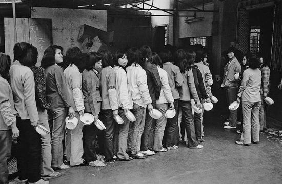 （1988年，广东东莞一家企业内排队进食堂的务工人员。图/视觉中国）