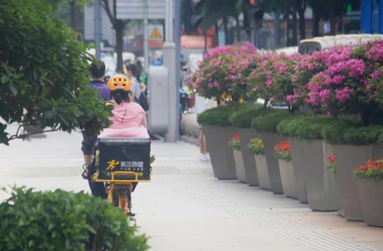 图 | 华强北商场楼下，一位女骑手快速驶过