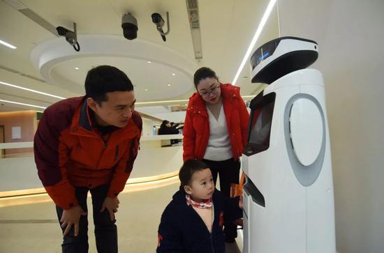 ▲2019年1月2日，杭州，居民在萧山区新办事服务中心与具有人工智能的机器人“小途”互动。