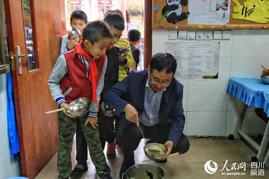 四川大学附属实验小学校长刘晏与孩子们一起打饭。朱虹 摄