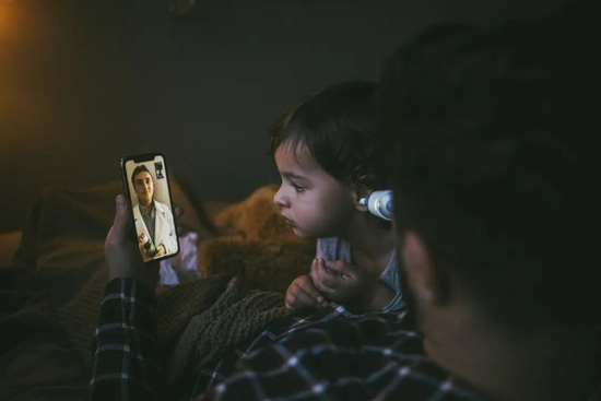 ■ 一位父亲在测女儿的体温，医生正和他们视频通话 / 盖蒂图片社（Maskat）