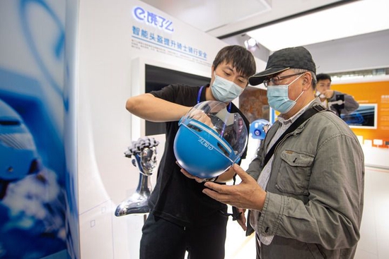 11月10日，阿里巴巴公司展台的工作人员向观众讲解智能头盔的工作原理。新华社记者 江汉 摄