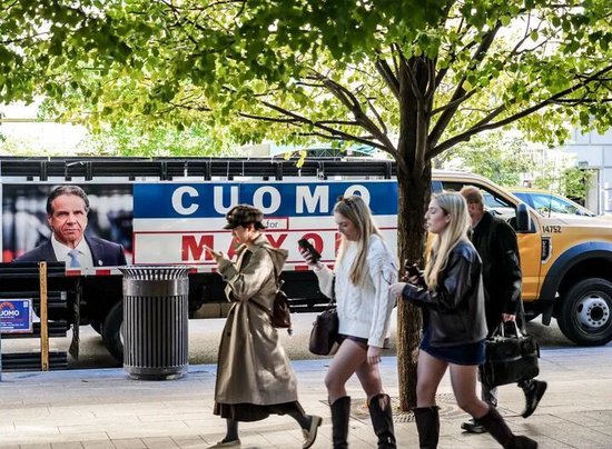  11月4日，在美国纽约，行人经过候选人安德鲁·科莫的竞选海报。新华社发（章正浩摄）