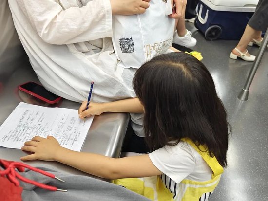 ▲&nbsp;2024年6月，武汉，小学一年级女生在地铁座椅上写作业。图 / 视觉中国