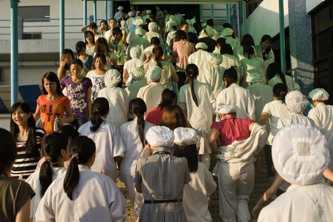 2011年8月19日，东莞市一电子厂的员工交接班时，上班的人和下班的人交织在一起（摄影/占有兵）