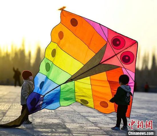 资料图:3月22日,敦煌市民在敦煌鸣沙山下党河大桥附近的空地上放风筝。 王斌银 摄
