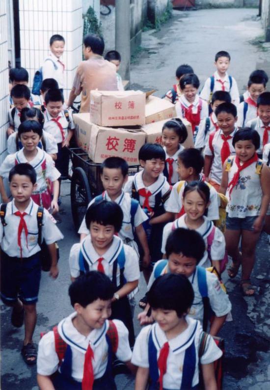 1987年,宗总骑着三轮车送演习本