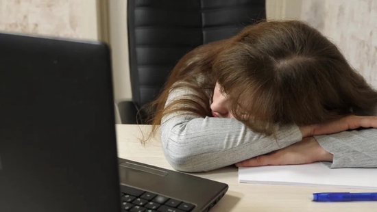 ▲资料图：一位女士趴在电脑前休息。