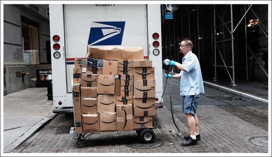 Axios报道截图：一名美国邮政局员工在运送亚马逊的包裹