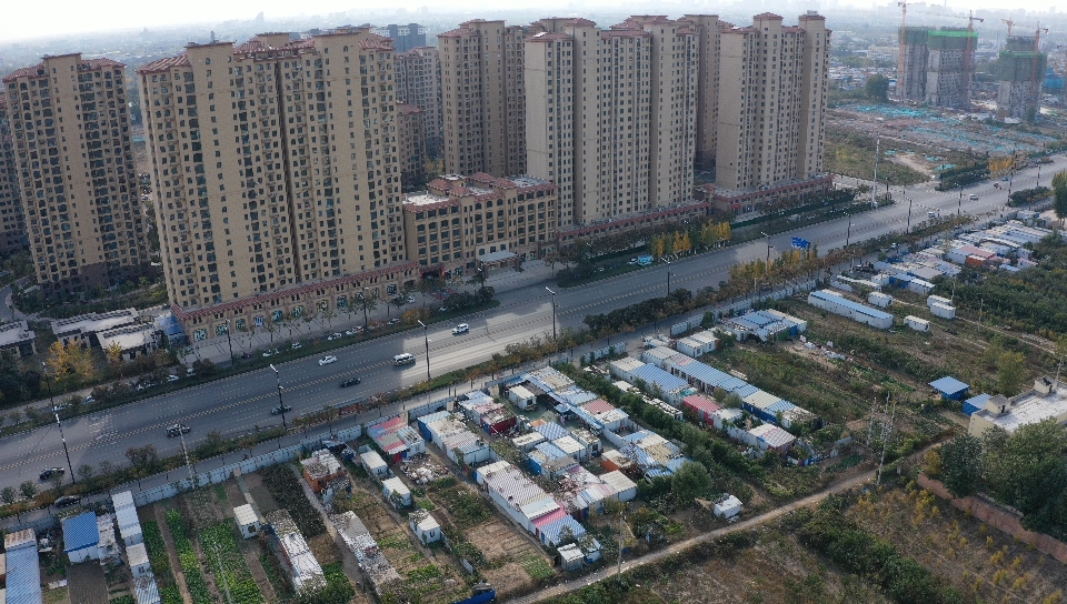 村民板房与新楼盘不过一路之隔。受访者供图