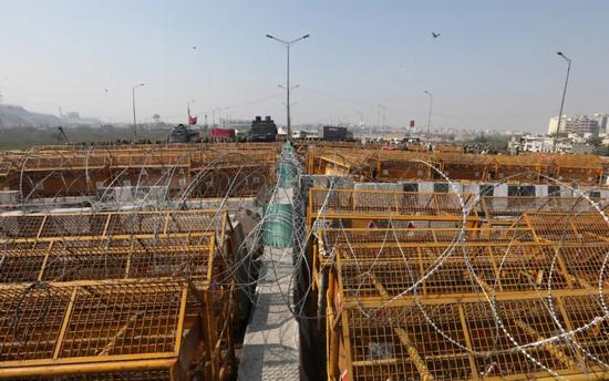 当地时间2月6日，印度新德里，数千名农民聚集在城郊，试图穿越由铁丝网和路障构成的封锁线，抗议政府推出的农业改革法案。警察驻扎在封锁线另一端，与农民形成对峙之势。图/IC photo