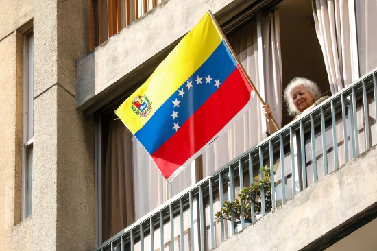 加拉加斯街头，一名女子手持委内瑞拉国旗参与游行，示威民众呼吁释放总统尼古拉斯・马杜罗及其夫人。