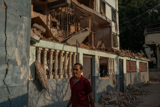 委内瑞拉拉瓜伊拉，一名男子走过一栋在美军军事干预中遭火箭弹袭击的公寓楼。