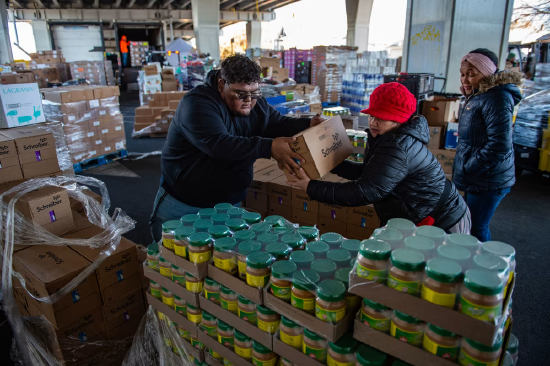 在美国马萨诸塞州切尔西市的 “合作组织” 食品分发站，工作人员和志愿者正整理捐赠的食品，准备分发给有需要的人。