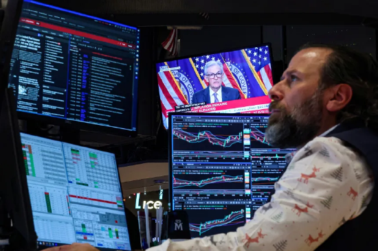 交易员正在工作，身后屏幕正播放鲍威尔的新闻发布会