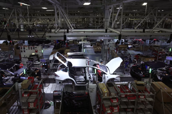 2018 年 7 月 18 日，美国加利福尼亚州弗里蒙特市的特斯拉工厂内，工人在生产线作业，一旁摆放着 Model X 和 Model S 车型。