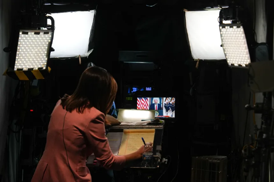 记者准备进行现场报道，背景是特朗普总统在白宫就伊朗战争发表讲话。