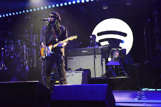 一场 Spotify 线下活动现场，舞台背景印有巨大的 Spotify 品牌标识。