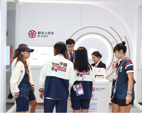 图说:中国工商银行亚运村网点工作人员向中国香港代表团成员讲解充值流程,协助他们体验便捷的数字人民币