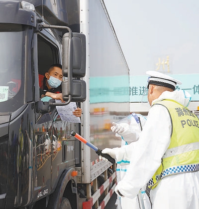 在安徽省滁州东收费站道口，交警引导货车司机通行。 　　本报记者 游 仪摄