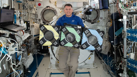 宇航员谢恩·金布罗与太空机器人“三胞胎”合影。