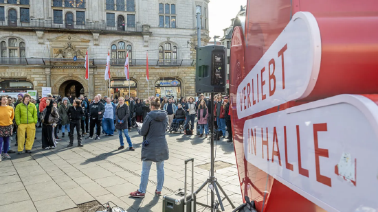  德国哈雷 ——2026 年 3 月 25 日：德国哈雷市文化、体育、青少年责任及社会服务机构代表与人人举行抗议行径，反对市议会拟议的预算削减谋划，行径标语为德语 “Die Kuh ist noch nicht vom Eis”（意为 “咱们尚未脱离窘境”）。因该市财政存在 1 亿欧元缺口，哈雷市议会当日召开会议，进一步议论大幅削减预算的奉行决策。