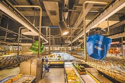 北京盒马鲜生超市十里堡店内,挂在金属链条上的分拣包在保护网上方