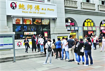 22日中午,江汉路地铁站D出口附近挂着“鲍师傅”招牌的糕点店门前,十几个人正在排队