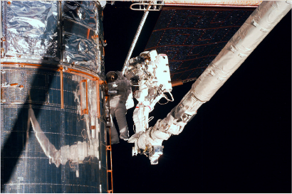 好意思国航天飞机航天员出舱站在机械臂上维修“哈勃空间千里镜”