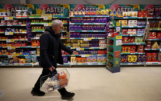 又名主顾走过乐购超市内摆放回生节彩蛋和巧克力的货架。