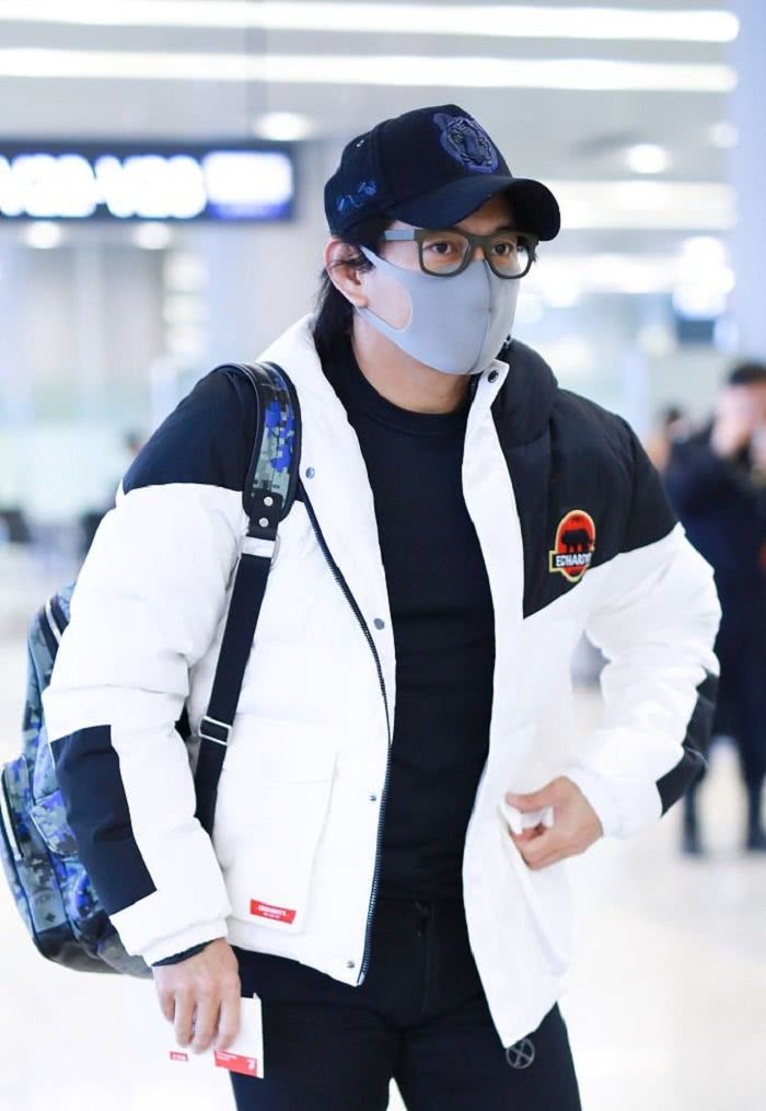 照片中的吴奇隆身穿着一件黑白凭借的外套,头戴着一顶黑色的帽子并且