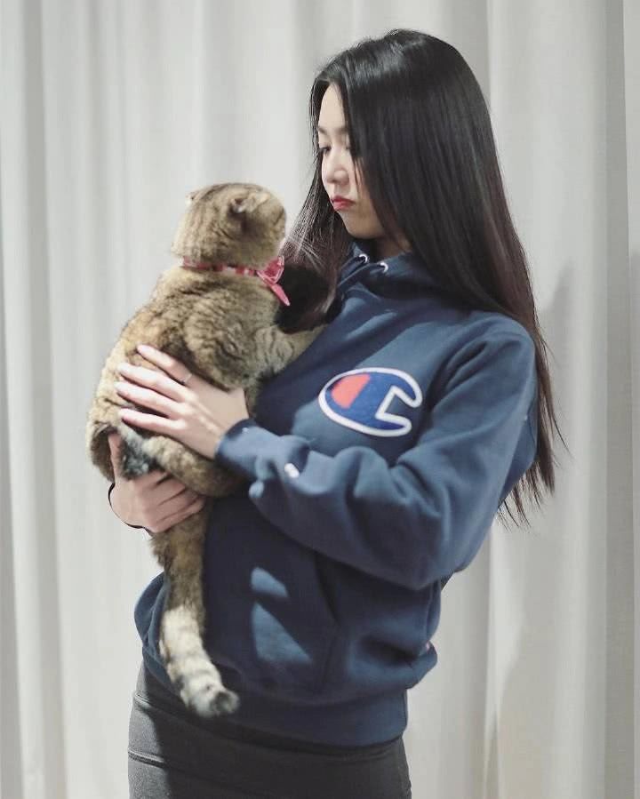 穿着一件蓝色的带帽卫衣和一件黑色打底裤的薛凯琪抱着软萌的小猫咪在