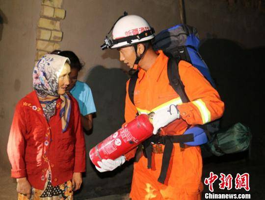 图为消防人员连夜入户排查，并给村民讲解灭火器用法。阿克苏地区消防支队提供 摄