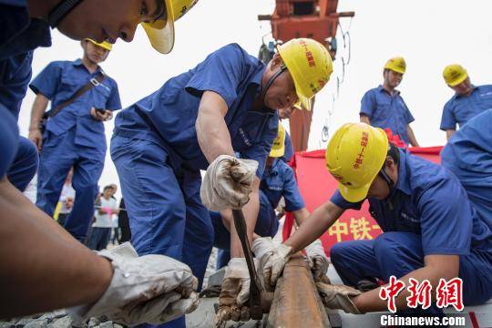 图为，9月21日，建设者在湖北省潜江市境内江汉铁路潜江北站进行最后一排钢轨铺设作业。徐云华 摄