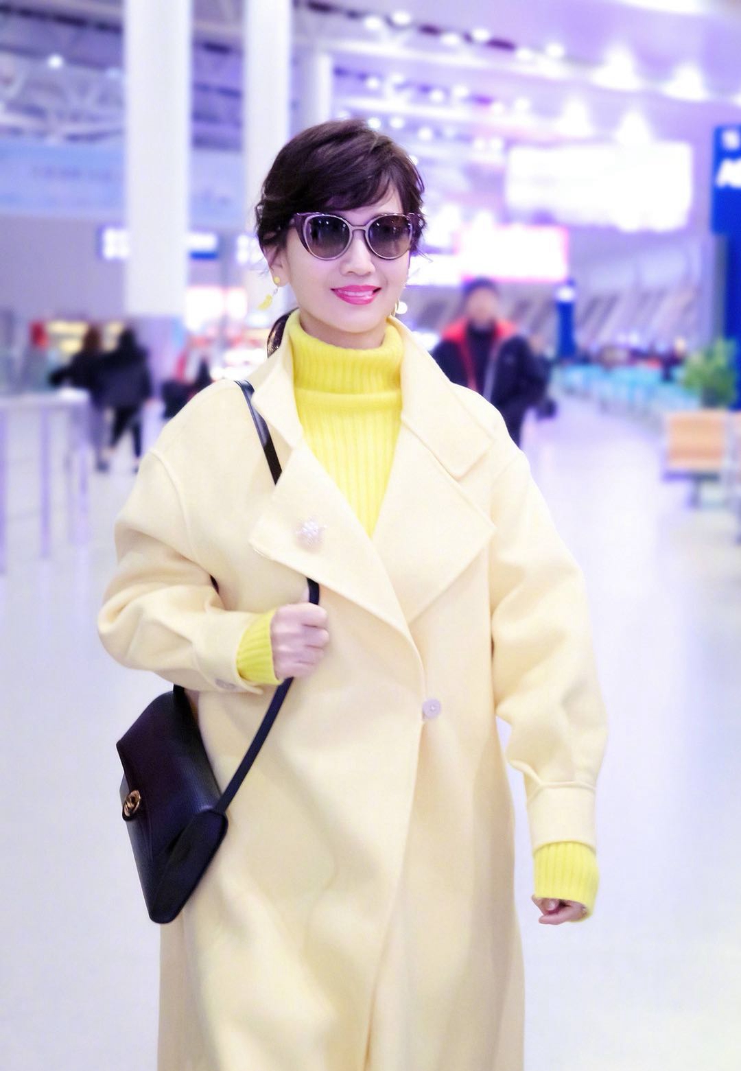 赵雅芝机场又穿黄色高领毛衣,这回搭配浅黄呢大衣,更显年轻!