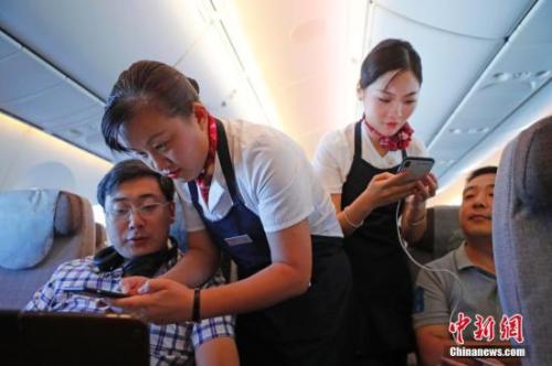 资料图：乘务员们在客舱内为旅客调试机上上网功能。中新社记者 殷立勤 摄