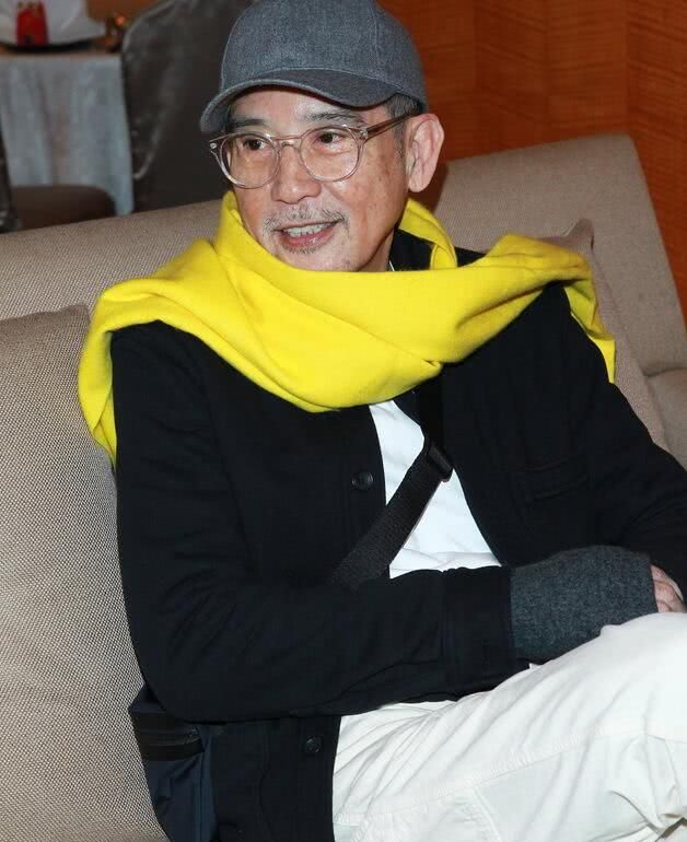 照片中的秦汉戴着灰色棒球帽,荧光黄色的围巾让他的皮肤看起来显得亮