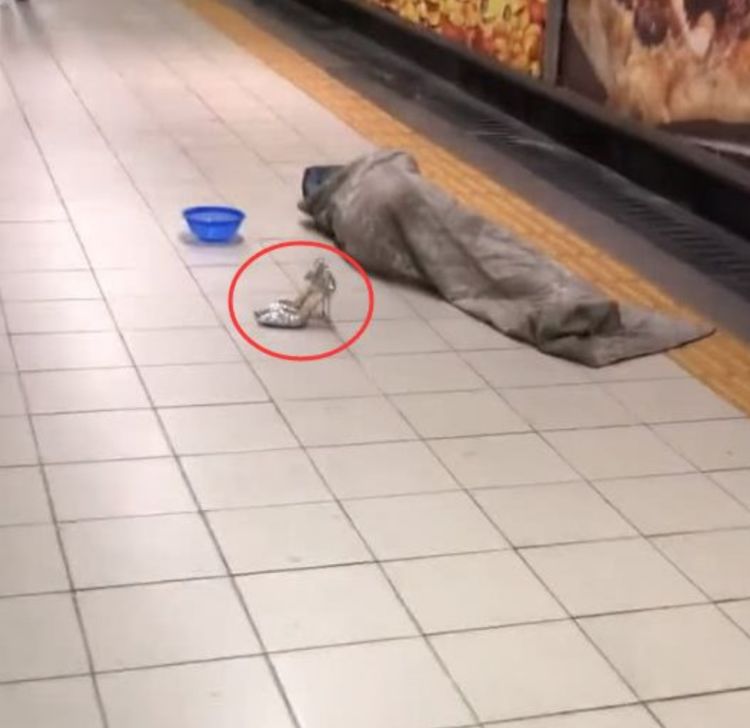 乞丐在地铁站裹着脏被子睡觉乞讨,一双豪华高跟鞋成了亮点