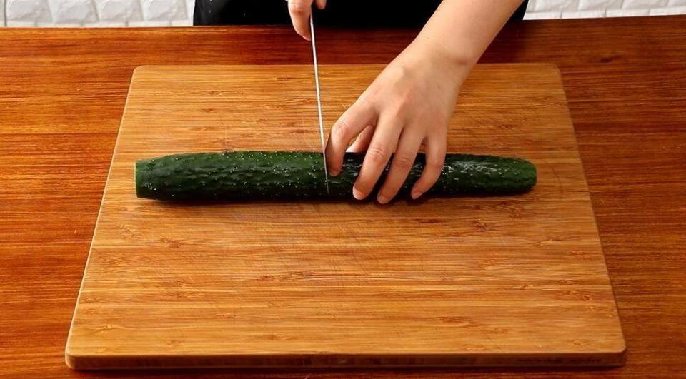 去掉黄瓜前后端,切成两段,两边垫上筷子,先正刀垂直将黄瓜切片.