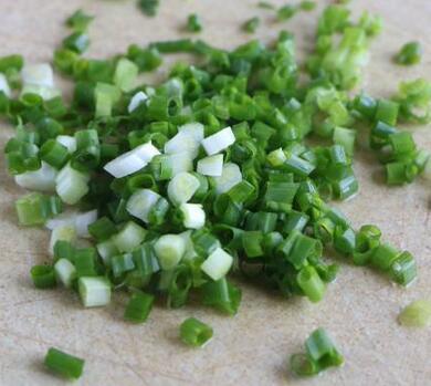 然后把鸡蛋打进碗里,放上面粉,把小葱碎也一起放进去,温水也一起全部