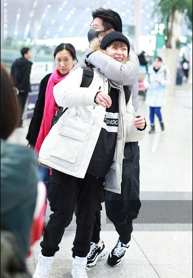 窦骁身穿银色厚羽绒服现身机场和女助理当众大玩"搂脖杀"
