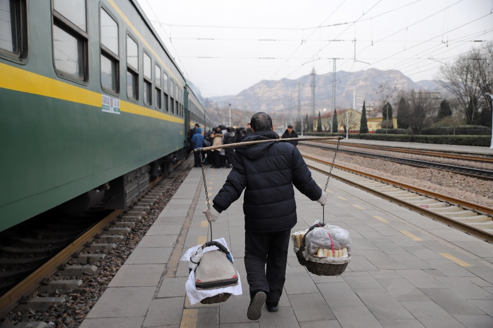 不是乘车去旅行,而是挑着土特产乘坐绿皮车去卖货,他们被称作"挑担工"